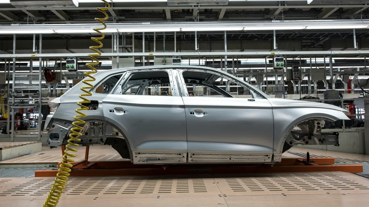 A silver car body on a production line in a factory.
